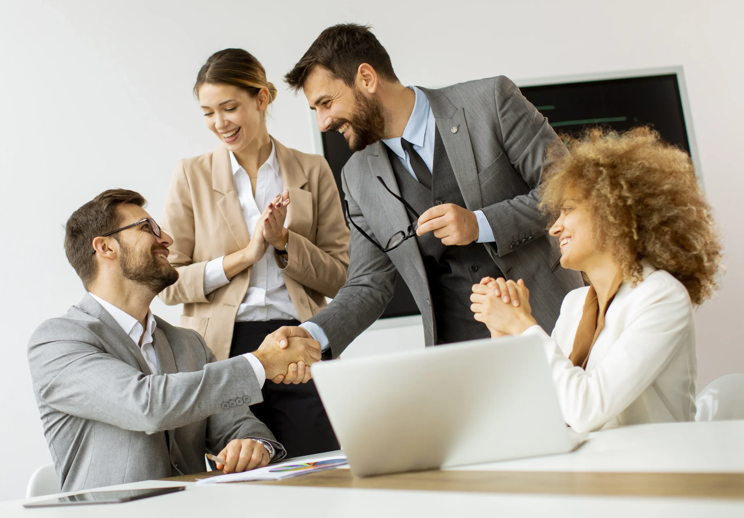 Business professionals celebrate successful negotiation with handshakes and smiles, reinforcing a seamless and positive purchasing experience for IT solutions