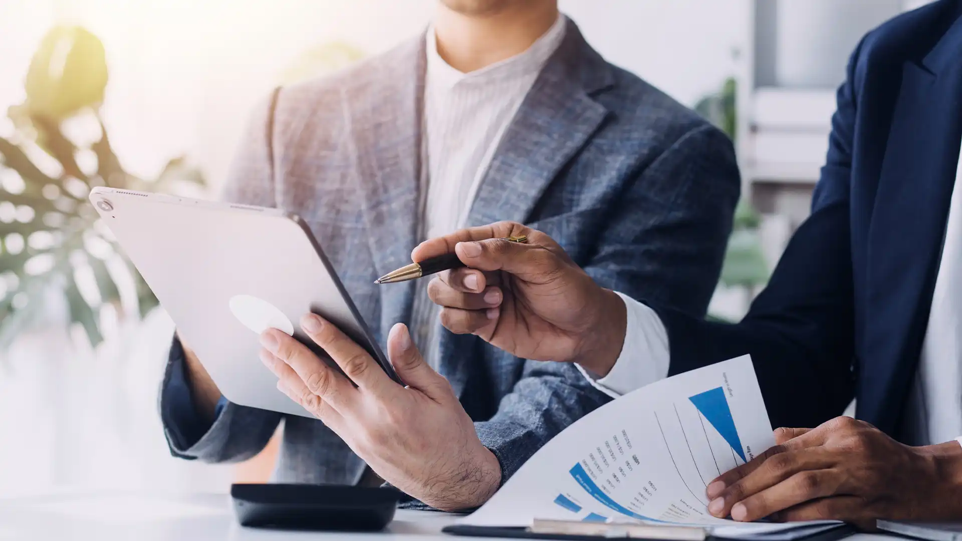 Two professionals analyzing financial data on a tablet, with one pointing to key metrics. This image symbolizes expert management of telecom expenses, ensuring businesses can focus on growth while costs are meticulously controlled