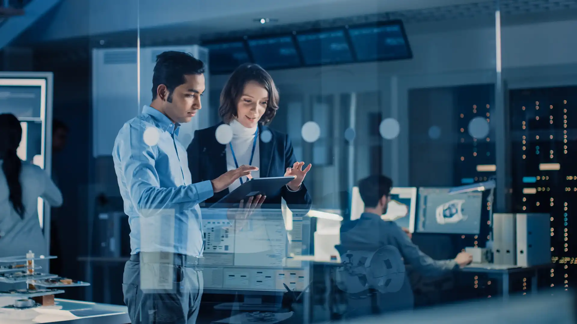 Two IT professionals in a server room strategize over a tablet, embodying Nimbl Networks' commitment to expert-driven, adaptive IT solutions that propel businesses ahead in the tech world